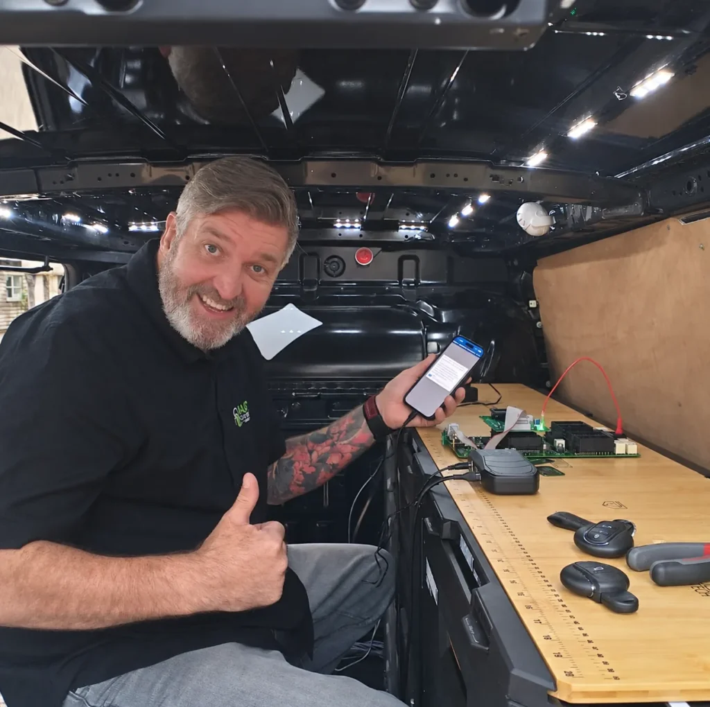 Nate of ND Auto Locksmiths in his mobile workshop van, programming a car key with diagnostic equipment and key fobs on the workbench
